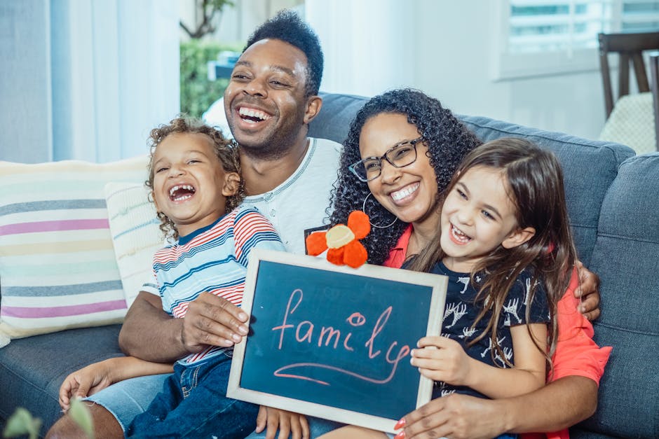 Cheerful family with kids holding a chalkboard at home, showcasing togetherness and love.